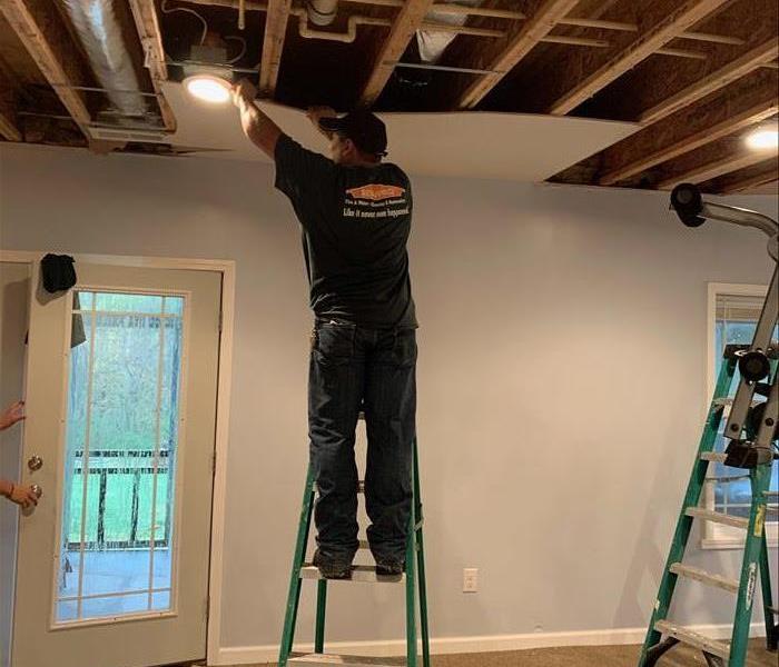 SERVRO associate cleaning the ceiling around light fixture